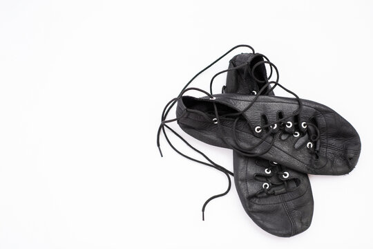 Pair of black leather Highland dance ghillies on white background with copy space