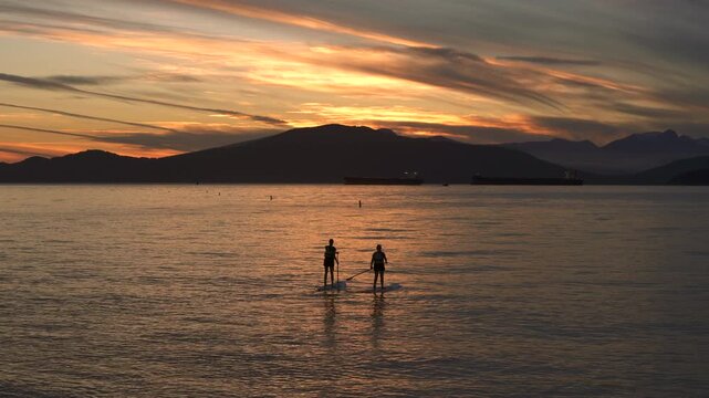 English Bay Sunset Paddleboarding Vancouver 4K UHD. Paddleboarding at sunset on English Bay at Jericho Beach. Vancouver, British Columbia. 4K. UHD.
