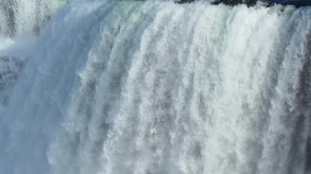Waterfall cascading with immense power over a rocky precipice into a deep misty canyon in 120fps 4K Slow Motion