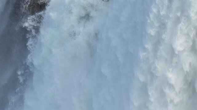 Waterfall crashing down with intense power creating heavy mist and white foam in a natural setting in 120fps 4K Slow Motion