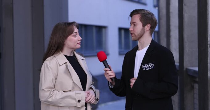 Professional journalist with microphone interviewing woman outdoors