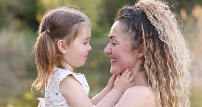 Mother with her cute little daughter in nature on sunny day. Camera moving forward