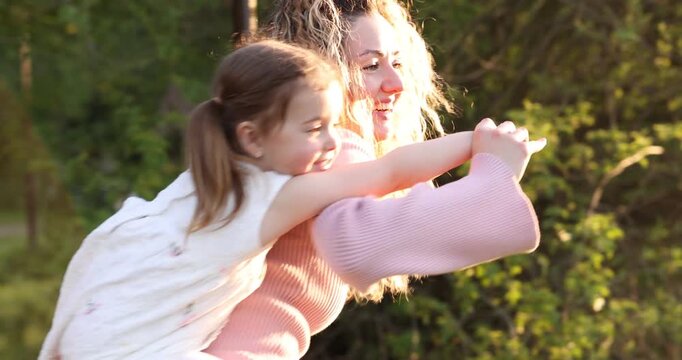 Mother spinning her cute little daughter in nature on sunny day. Camera moving forward and backwards