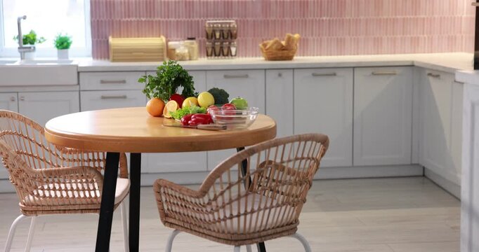 Fresh vegetables and fruits on wooden table in kitchen, camera moving down