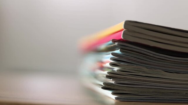 Many lifestyle magazines on wooden table, closeup. Camera moving up