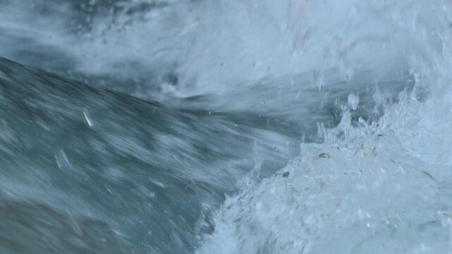 River water rushing and splashing over rocks in a mountain stream creating white foam and bubbles in 120fps 4K Slow Motion