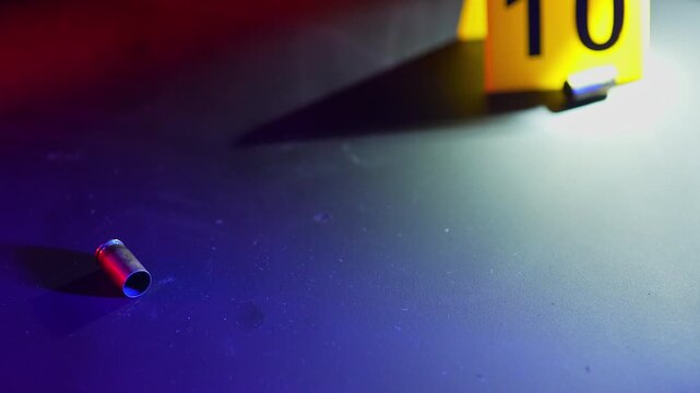 Bullet shells casing with flashing police lights at night. Fire truck or police car flashing lights. Educational concept of crime Scene restricted area for investigation with yellow evidence markers.