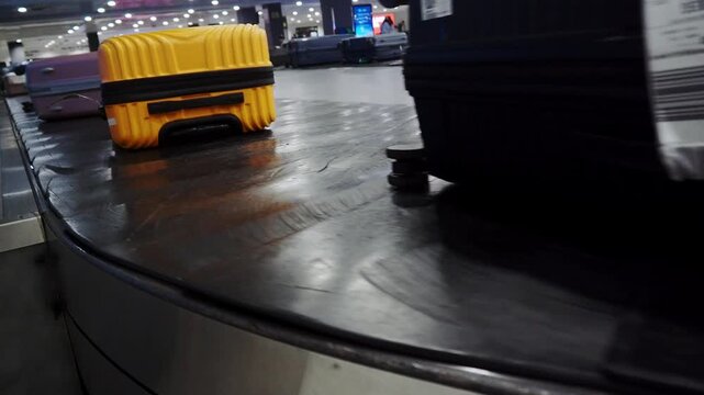 4K baggage carousel with purple, yellow and black suitcases moving left to right in the Tbilisi airport terminal.