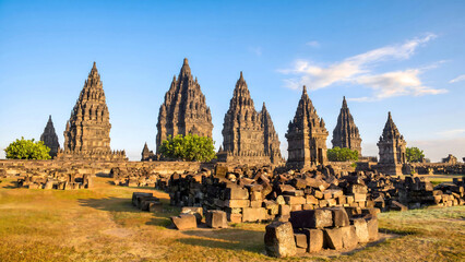 Fototapeta premium Ancient Hindu temple complex with tiered spires and stone ruins under blue sky