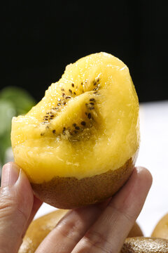 Fresh New Zealand Golden Yellow Kiwi Fruit Half with Seeds Held in Hand - Healthy Tropical Nutrition