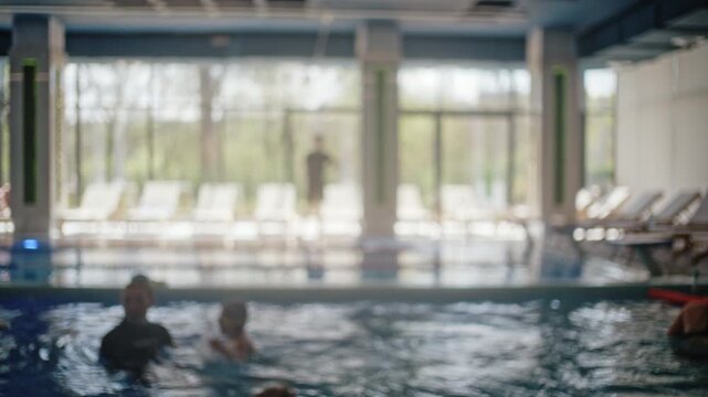 Blurred view of children swimming assisted by instructors during swimming lessons