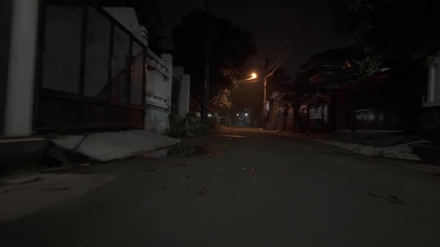 Low angle driving view through a quiet suburban street at night with dim streetlights