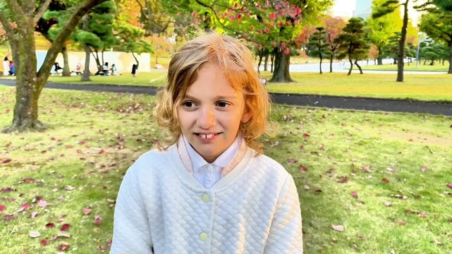  Young blonde girl picking her nose in a park during autumn