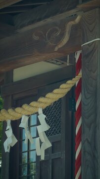 Close-up of traditional Japanese wooden shrine architecture with sacred Shimenawa rope and Shide streamers
