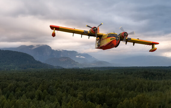 Yellow-Red Water Bomber Seaplane Firefighting Aircraft Flying Over Forested Mountains In BC Canada