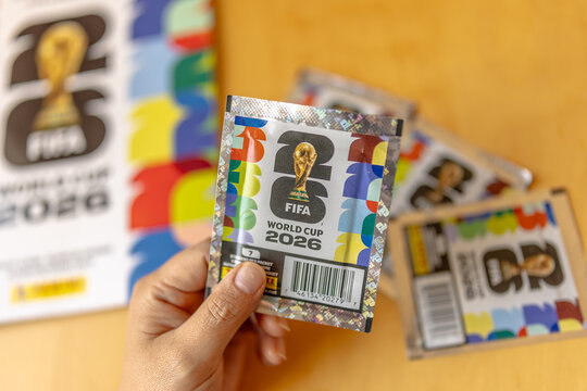 Calgary, Alberta, Canada. May 15, 2026. A hand holds an official Panini FIFA World Cup 2026 sticker packet over an album on a table.