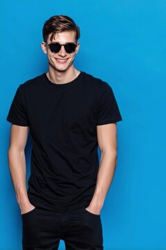 Handsome young man in black tshirt posing against blue background
