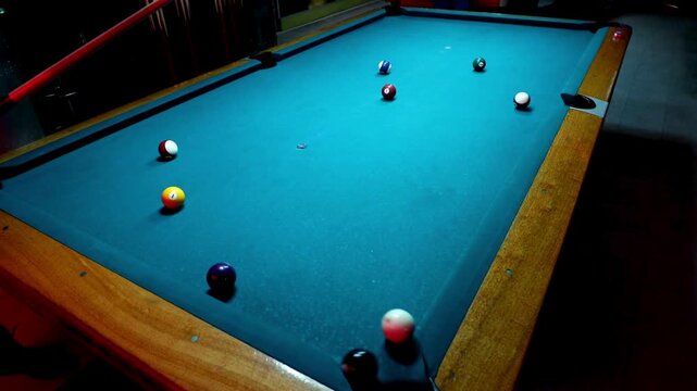 Person playing pool on a blue table with colorful balls and cue stick