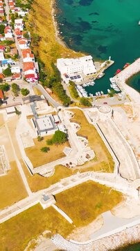 Vertical video. Seddulbahir, Eceabat, Turkey. Restored Ottoman Seddulbahir Fortress, angular stone bastions and coastal ramparts, aerial view over turquoise Dardanelles Strait on a clear sunny day. A