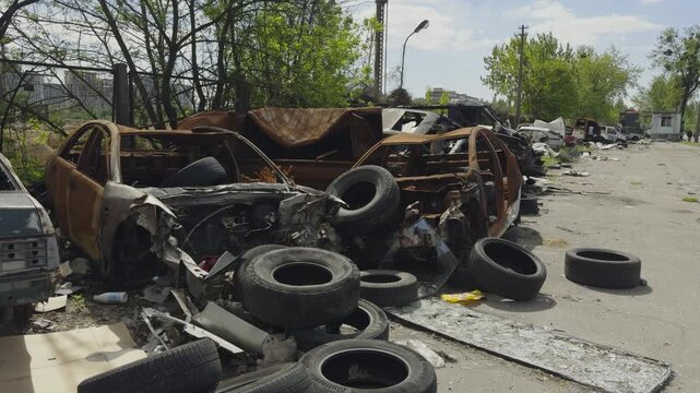 Burned Car Shells and Old Tires in Abandoned Junkyard. Damaged Metal Carcasses for Scrap Recycling. Auto Disposal and Environment Pollution