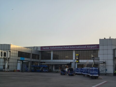 Passenger view of Sardar Vallabhbhai Patel Airport apron with IndiGo ground equipment and terminal operations. Travel, aviation and mobility scene featuring Adani management and Air India links today.
