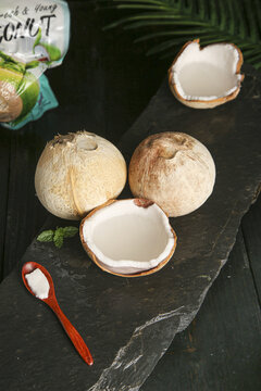 Freshly opened young coconuts with white meat on slate board - tropical fruit ingredient for Thai cuisine and pressed juice