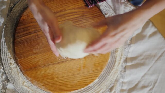 Top view of woman hands kneading fresh dough on wooden board in kitchen for homemade bread baking.