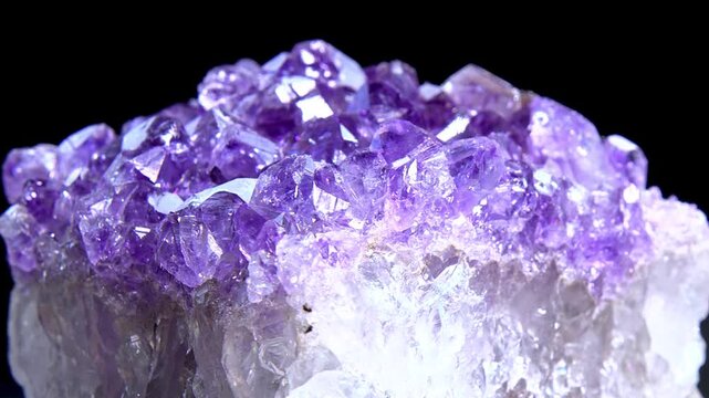Beautiful raw amethyst mineral cluster rotating on black background video.