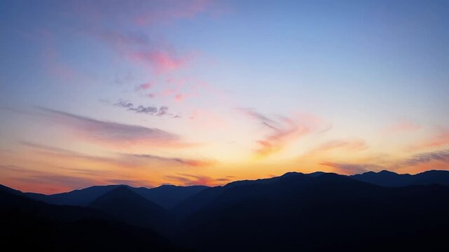 A mesmerizing aerial view capturing a thick rolling sea of clouds nestled between layered mountain peaks during dawn in the mountains of China.