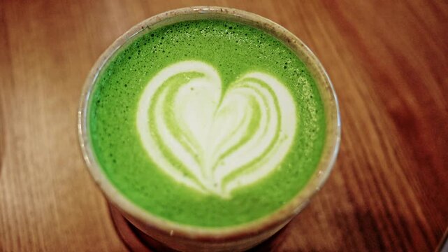 Top down close up of a matcha latte served in a ceramic cup on a wooden table