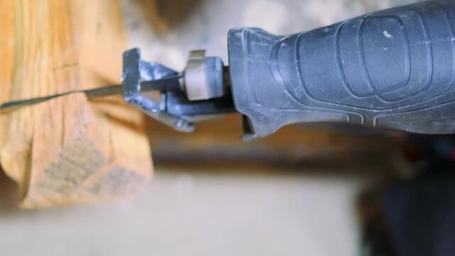 Reciprocating saw blade cutting wooden beam in close-up, portable demolition power tool for construction, carpentry, renovation and repair projects.
