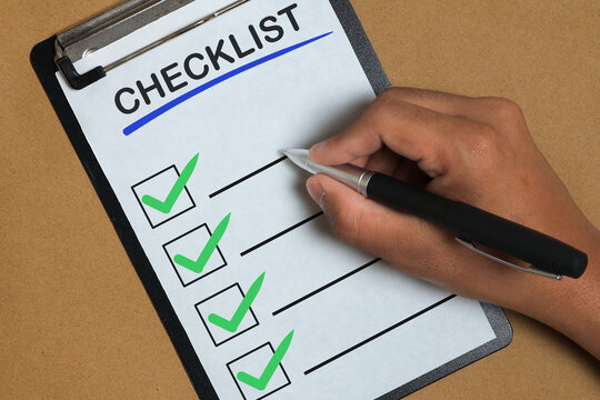 Business Checklist Completion with Hand Ticking Tasks on Clipboard