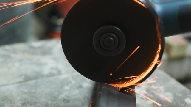 Angle grinder cutting metal with bright sparks in close-up, powerful industrial power tool for construction, fabrication, welding and metalworking process.