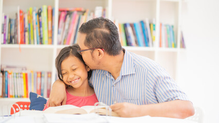 Obraz premium Loving Father Kissing Daughter on Head While Reading Together in Library