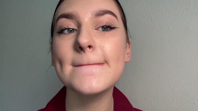 Woman applying shiny lip gloss, a liquid cosmetic, to her full lips using an applicator, detailing her meticulous beauty routine, performing self-care grooming.