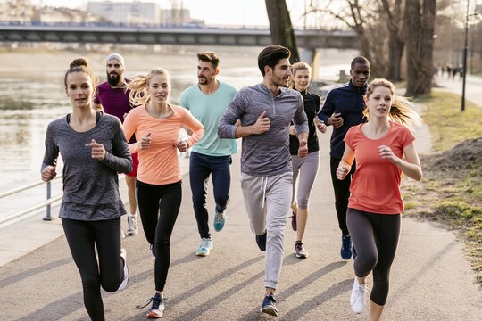 Young adults jogging together in urban riverside park