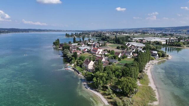 Panorama flight backwards away from church Basilica of Sts. Peter and Paul on island Reichenau over Lake Constance (Bodensee) near Konstanz, Germany
