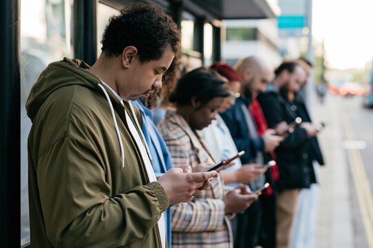 Young commuters checking mobile phones at city transit station