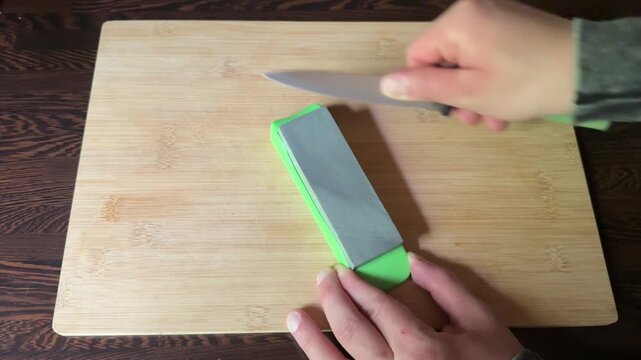 Sharpening kitchen knives on whetstone close up