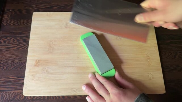 Sharpening kitchen knives on whetstone close up
