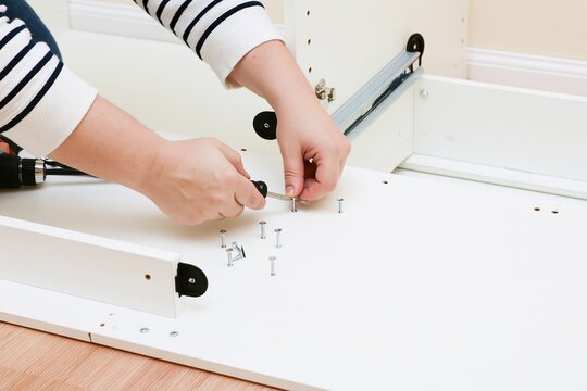 Hands assembling flat pack furniture with screwdriver
