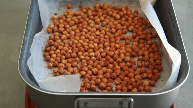 Close-up of crispy, seasoned baked chickpeas cooling on a metal baking tray right out of the oven