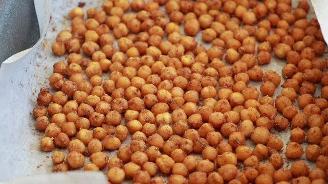 Close-up of crispy, seasoned baked chickpeas cooling on a metal baking tray right out of the oven