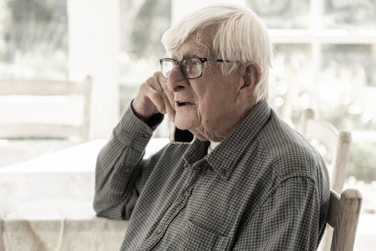 elderly man talking on cellphone at home