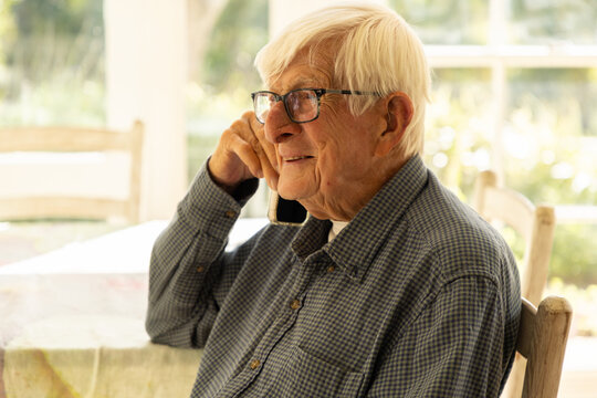 elderly man talking on cellphone at home