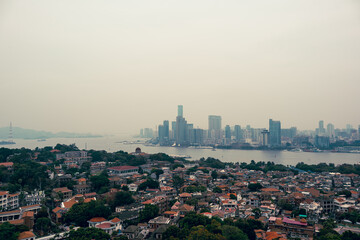 Obraz premium Scenic overlook of Xiamen Shimao Twin Towers and urban buildings from Gulangyu Island. Coastal city skyline blends modern high-rises with seaside natural scenery perfectly.