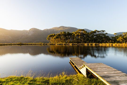 wooden launch overlooking placid pond at sunset, overlooking Klein Mountains, Stanford, South Africa