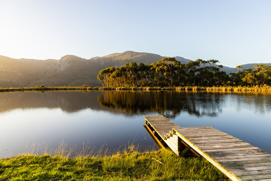 wooden launch overlooking placid pond at sunset, overlooking Klein Mountains, Stanford, South Africa