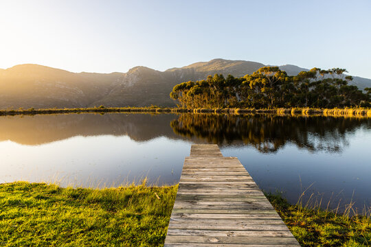 wooden launch overlooking, placid pond at sunset, overlooking Klein Mountains, Stanford, South Africa