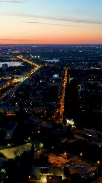 Vertical video. Lipetsk, Russia. Drone footage of Prospekt Mira and the Left Bank District at twilight, showing illuminated streets stretching across the Voronezh River with city lights fading into t